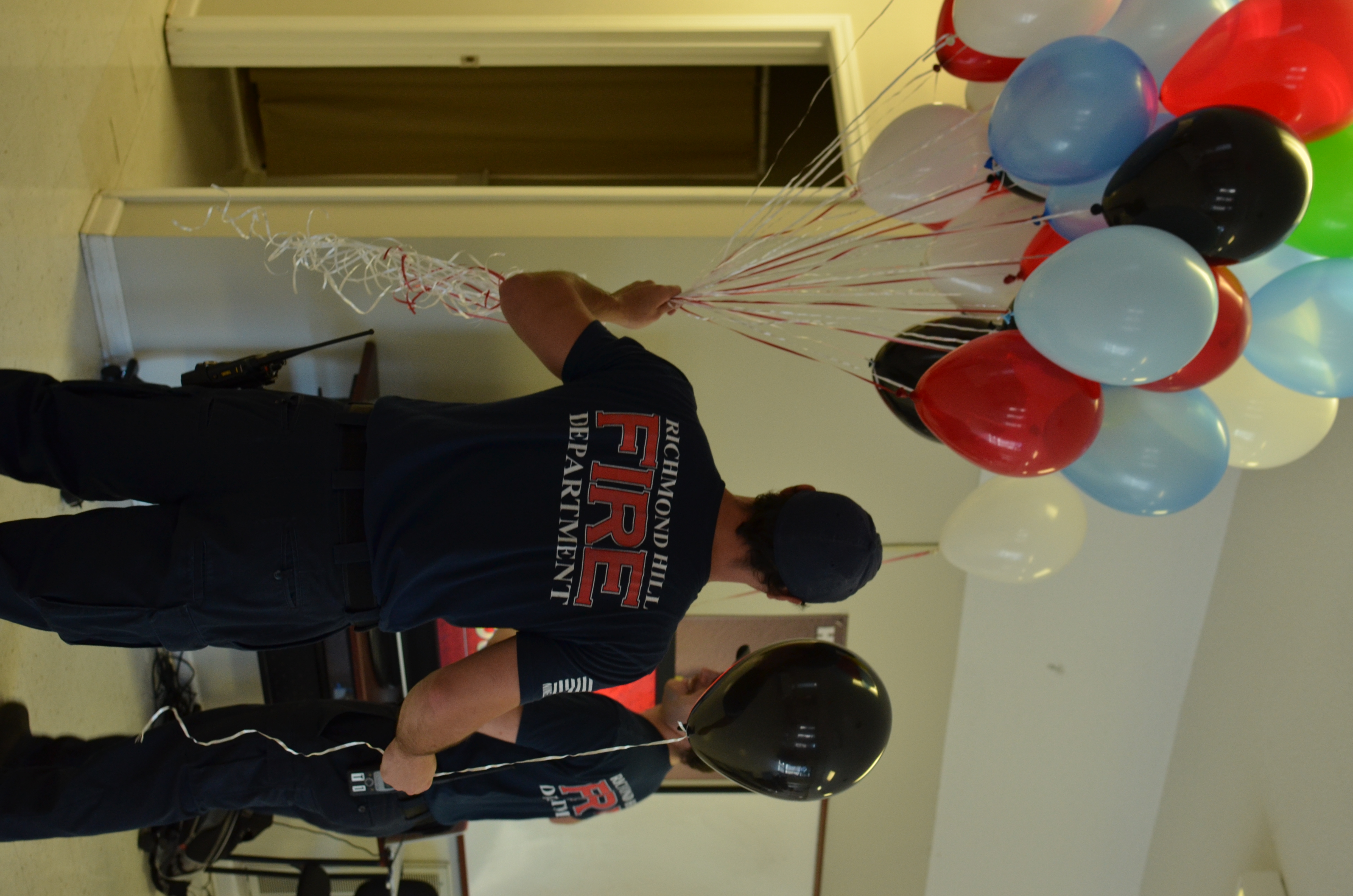 firefighter holding red, white, blue, and black balloons