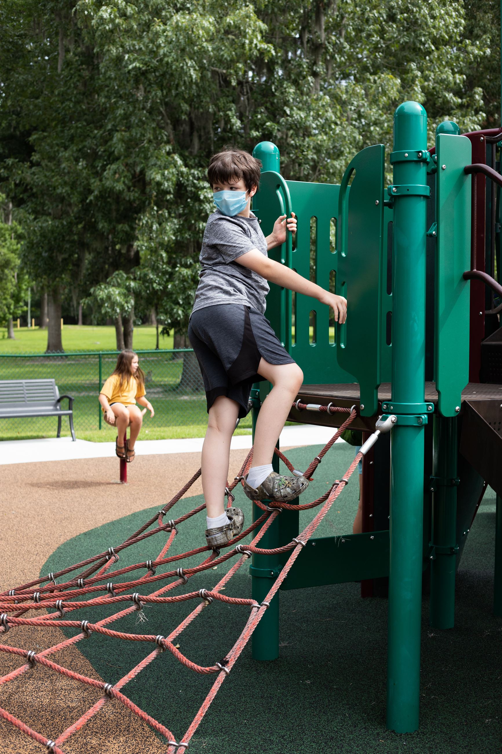 boy climbs on playground equipment